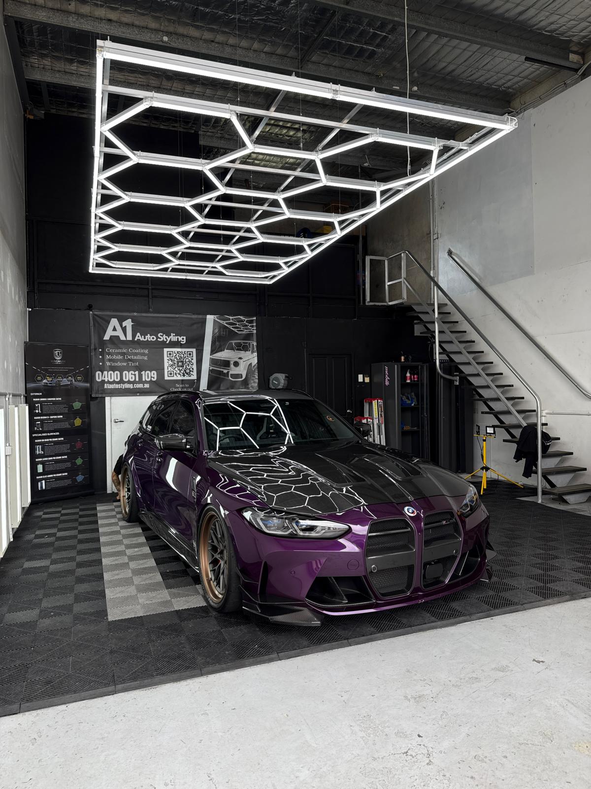 Purple BMW M3 G80 in the A1 Auto Styling workshop after a premium ceramic coating, hexagonal LED ceiling reflected on the panels